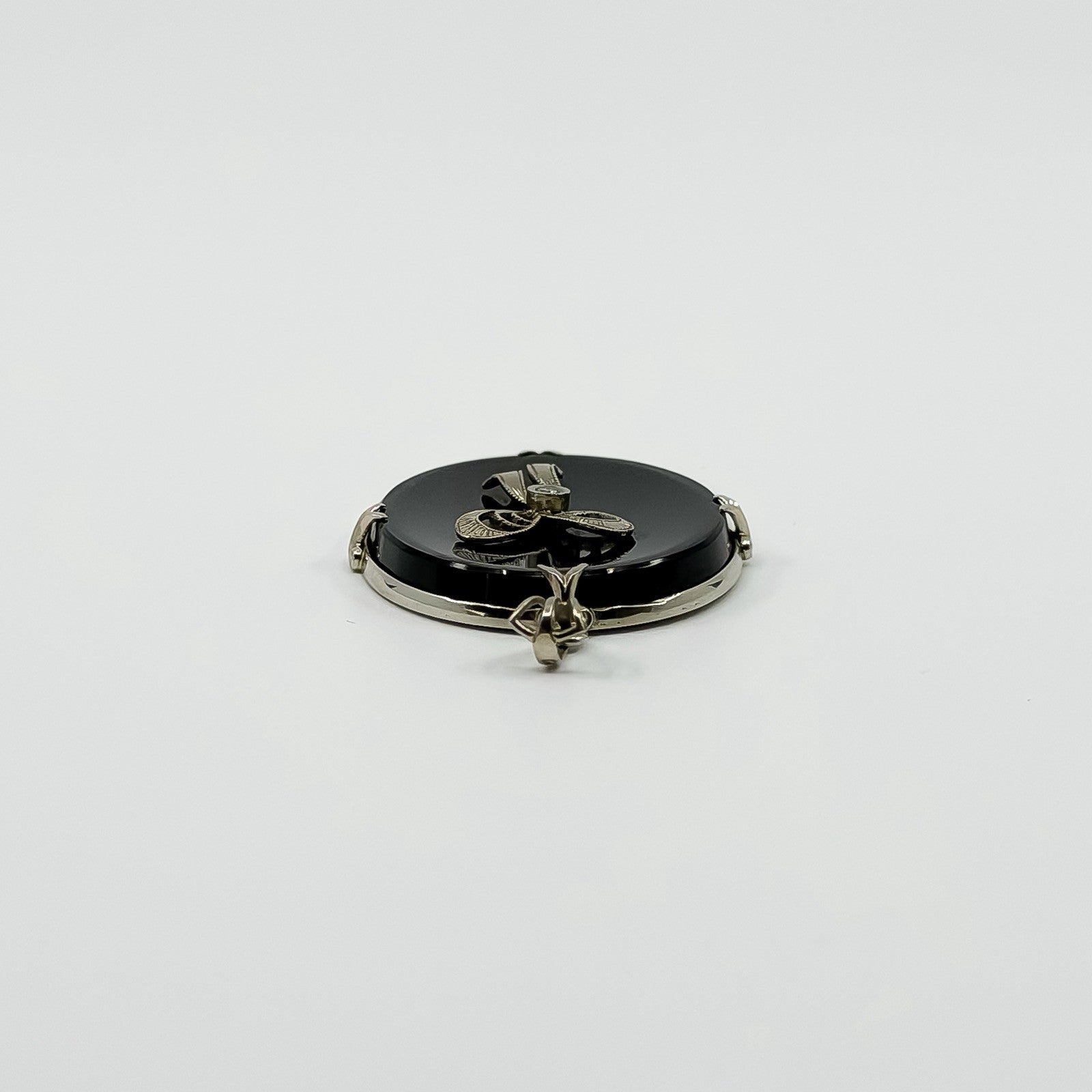 Low front view of vintage black onyx bow pendant showing raised bow detail and oval onyx.