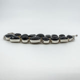 Side profile of chunky sterling silver black onyx bracelet showing raised cabochon bezel settings