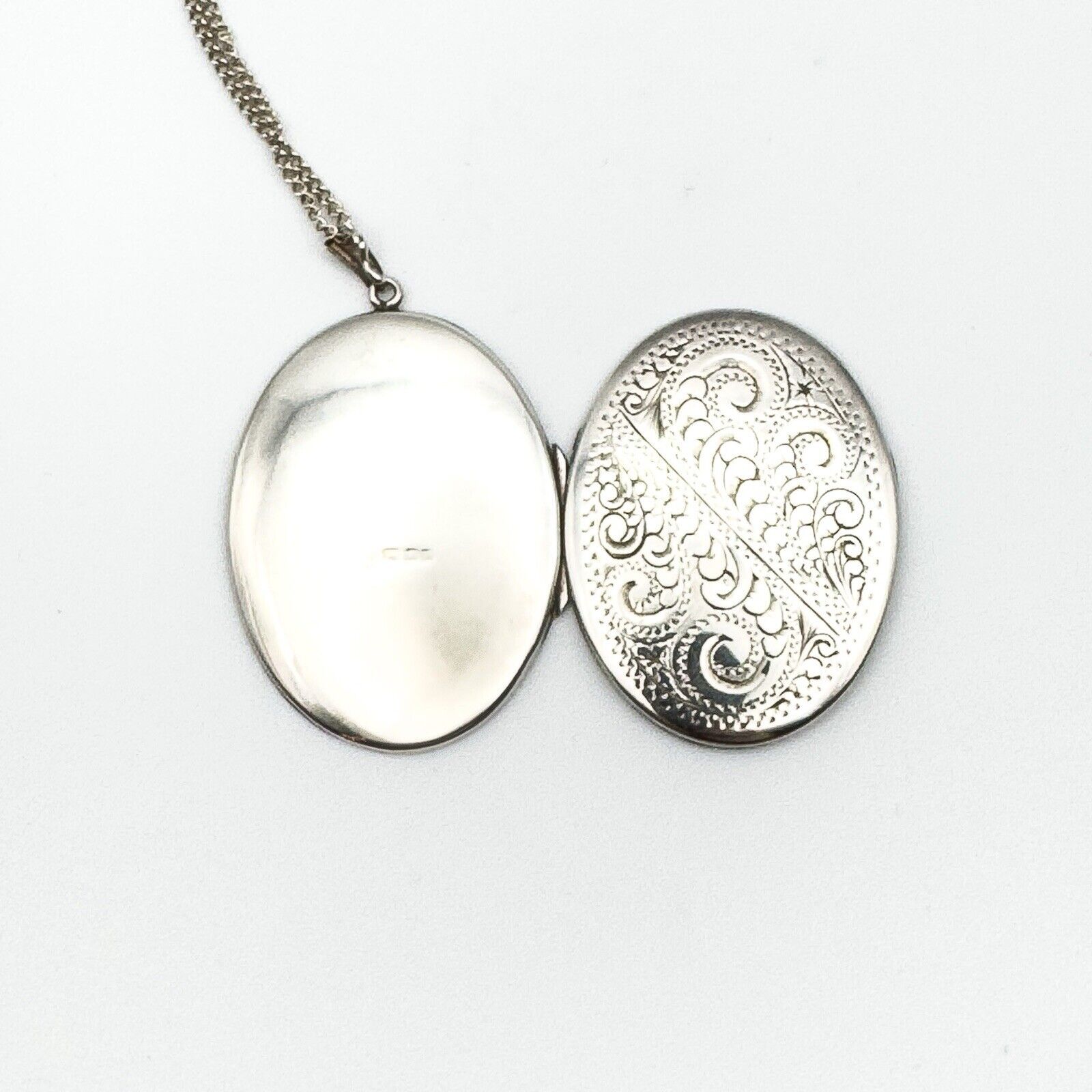 Outside of vintage oval silver locket showing hallmark on one side