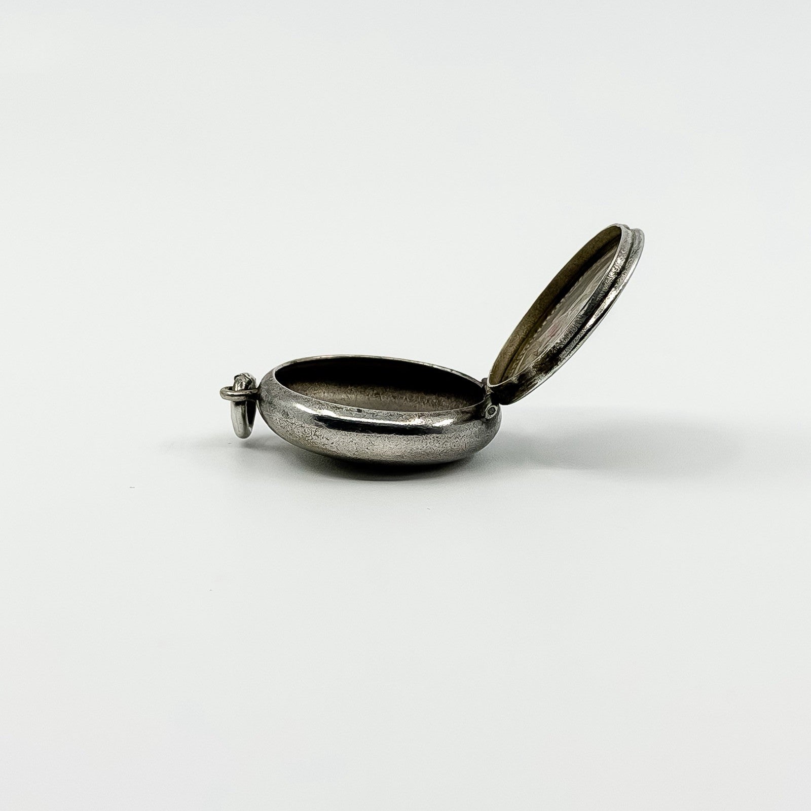 Open side profile of vintage sterling silver Virgin Mary photo locket showing the photo compartment.