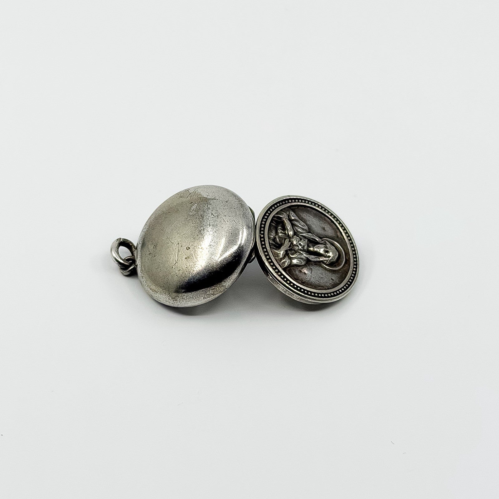 Open vintage sterling silver Virgin Mary photo locket showing plain back and raised religious detail.