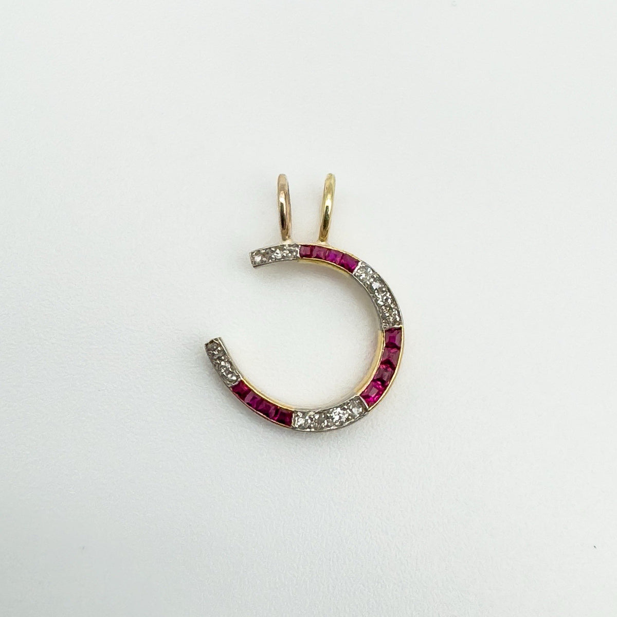 Overhead view of antique horseshoe pendant with ruby and diamond detail
