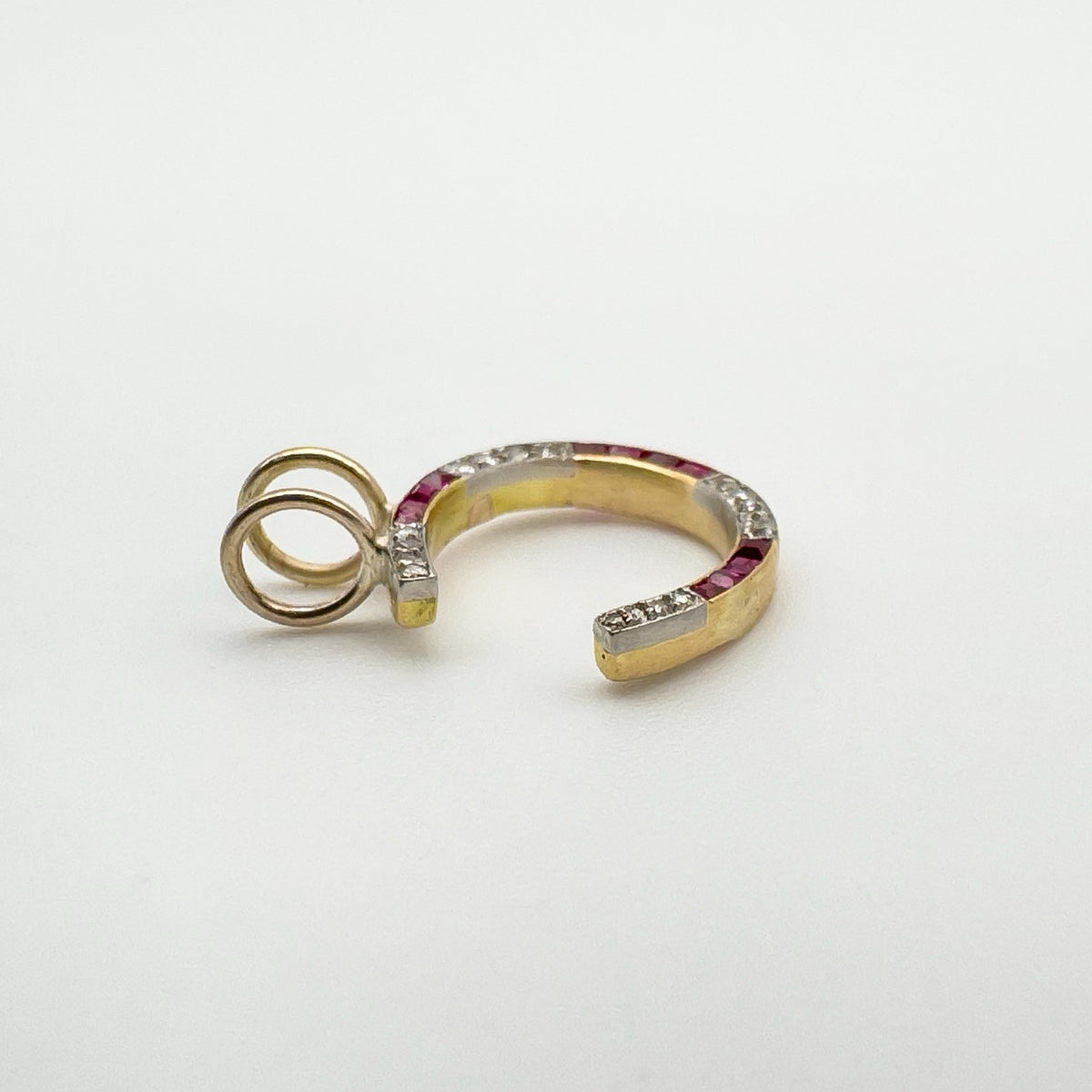 View of ruby and diamond horseshoe pendant showing depth and gold finish