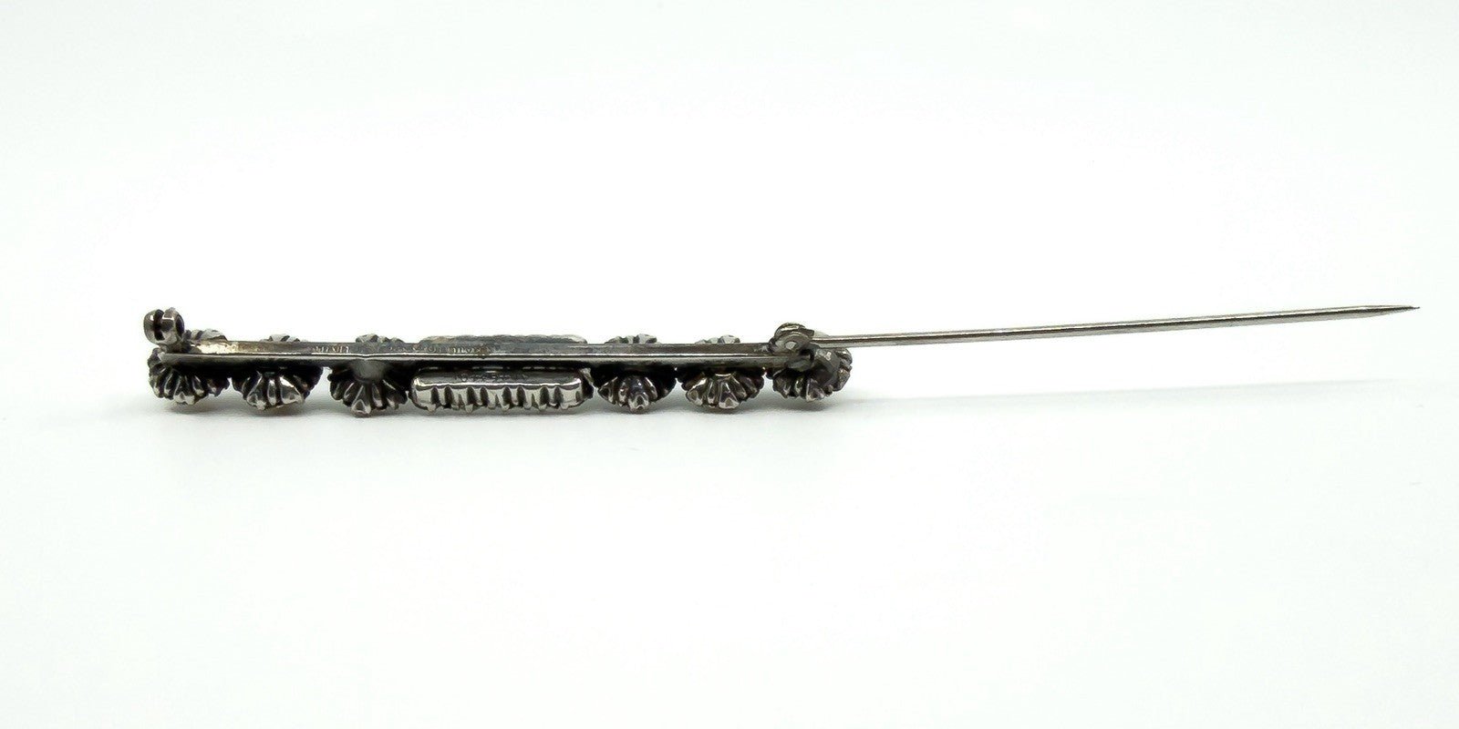Side view of the paste and pearl bar brooch with pin open, showing the long needle and hinge.