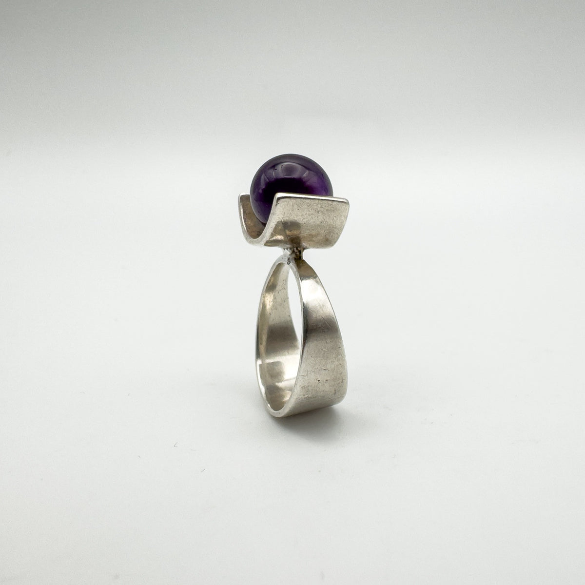 Profile view of bold vintage ring with purple amethyst and wide silver band