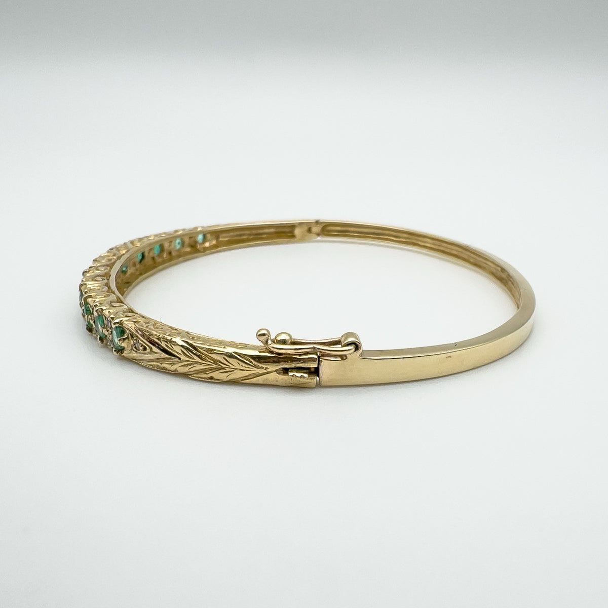 Side angle showing secure clasp on oval emerald and diamond bangle