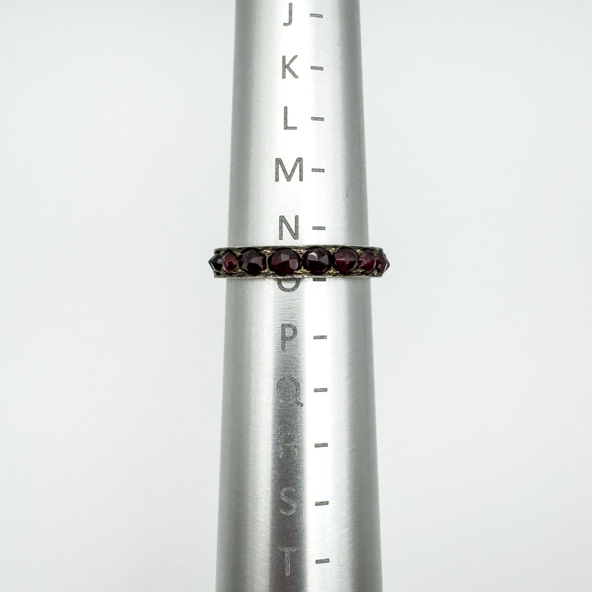 Vintage garnet eternity ring on sizer showing UK ring size N to O