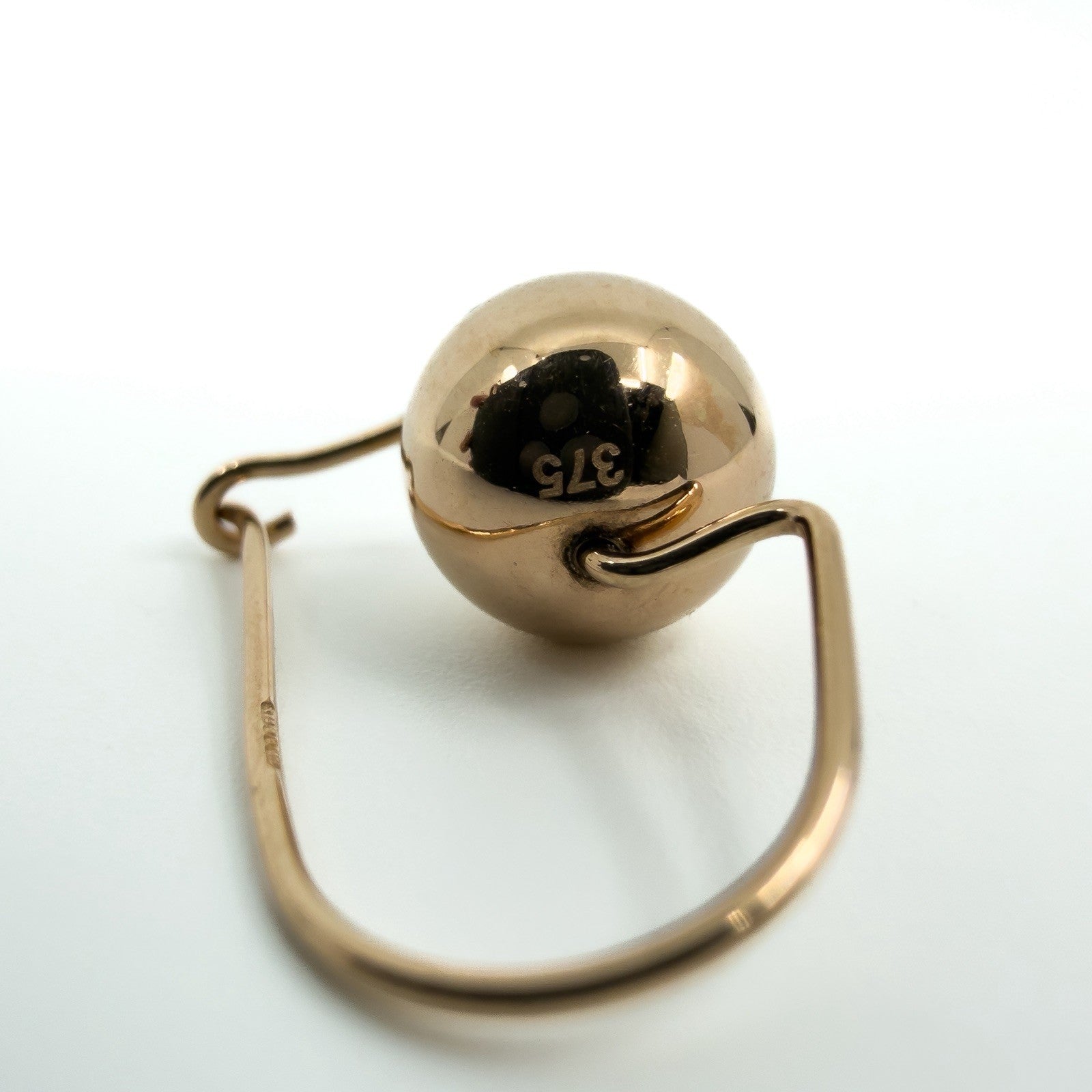 Close-up of 9ct rose gold ball earring showing polished bead and curved hook wire
