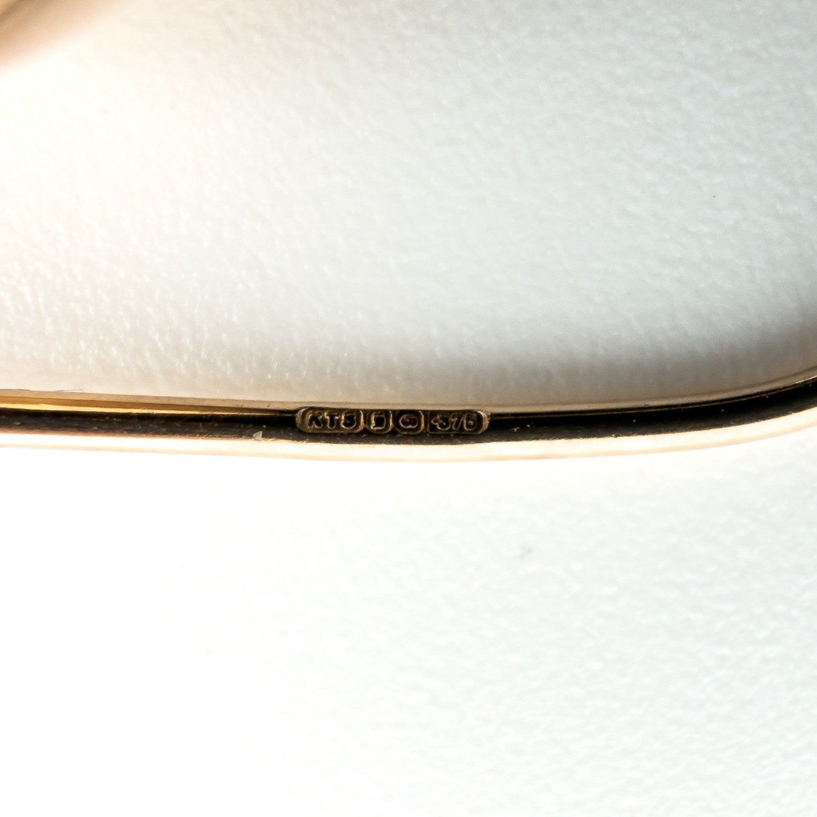 Close-up of 9ct rose gold earring wire stamped 375 with hallmark details visible