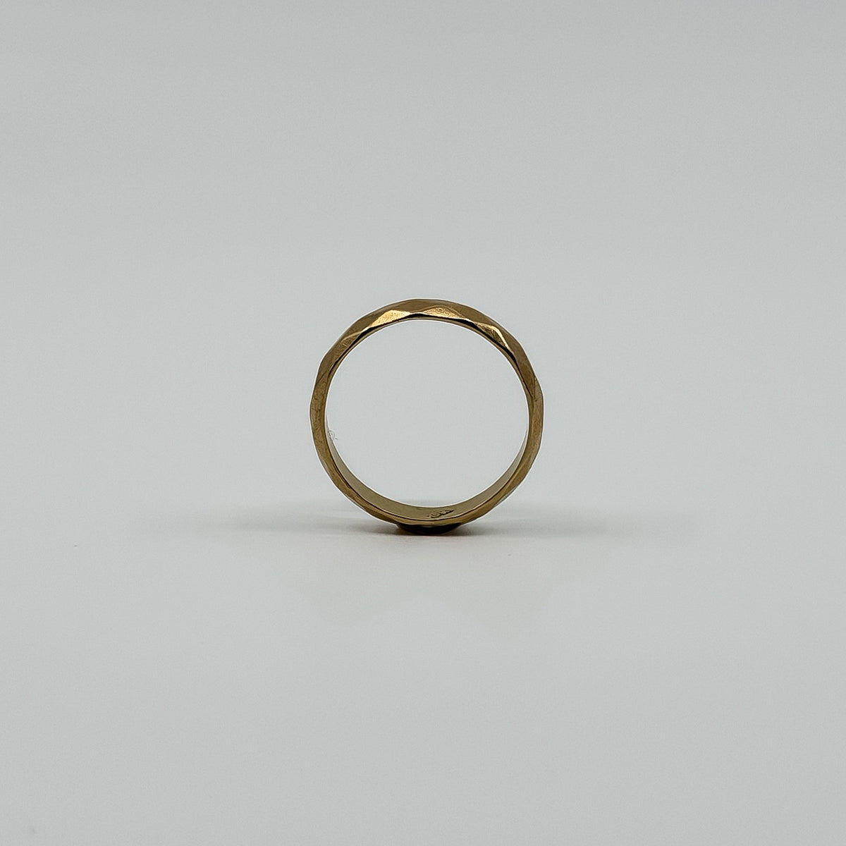 Upright view of vintage 18ct rose gold faceted band ring showing the full round profile.