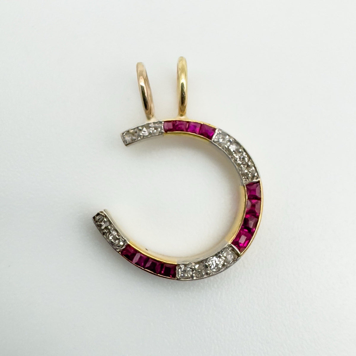 Antique 9ct gold horseshoe pendant with rubies and diamonds in channel setting
