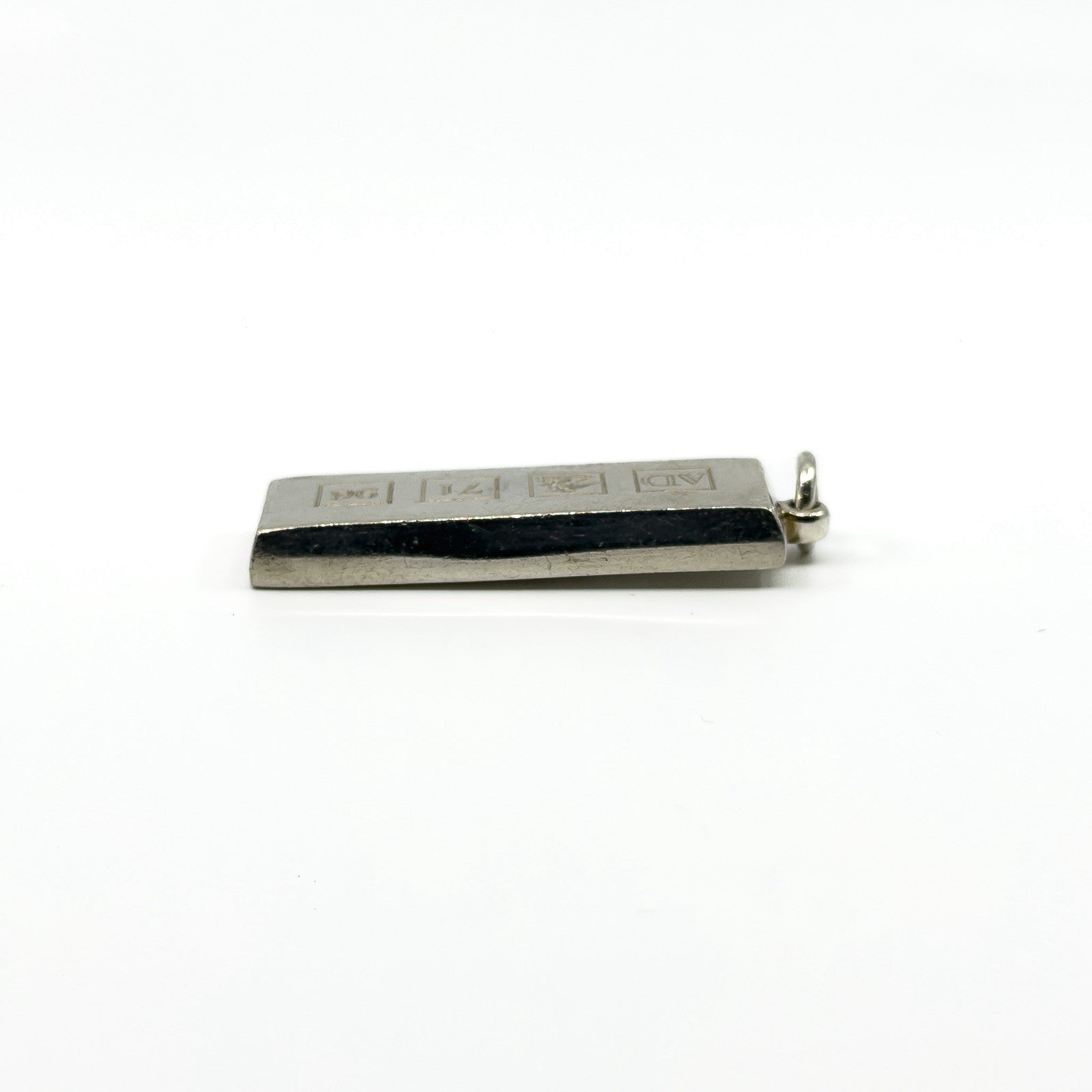 Low side view of the sterling silver ingot pendant with hallmark blocks along the front.