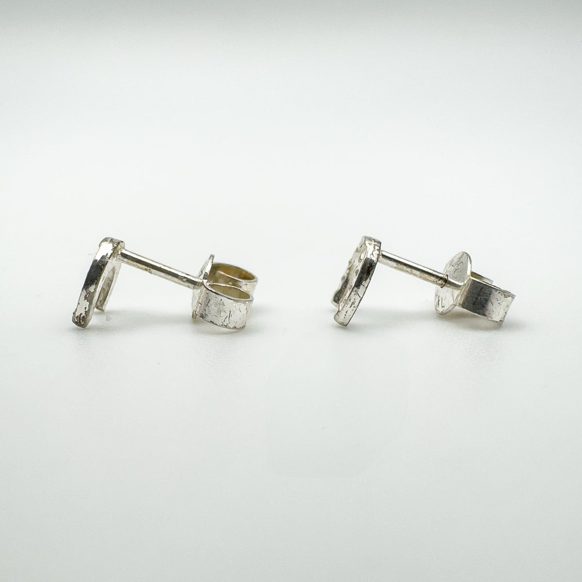 Side profile showing silver horseshoe studs and butterfly backs