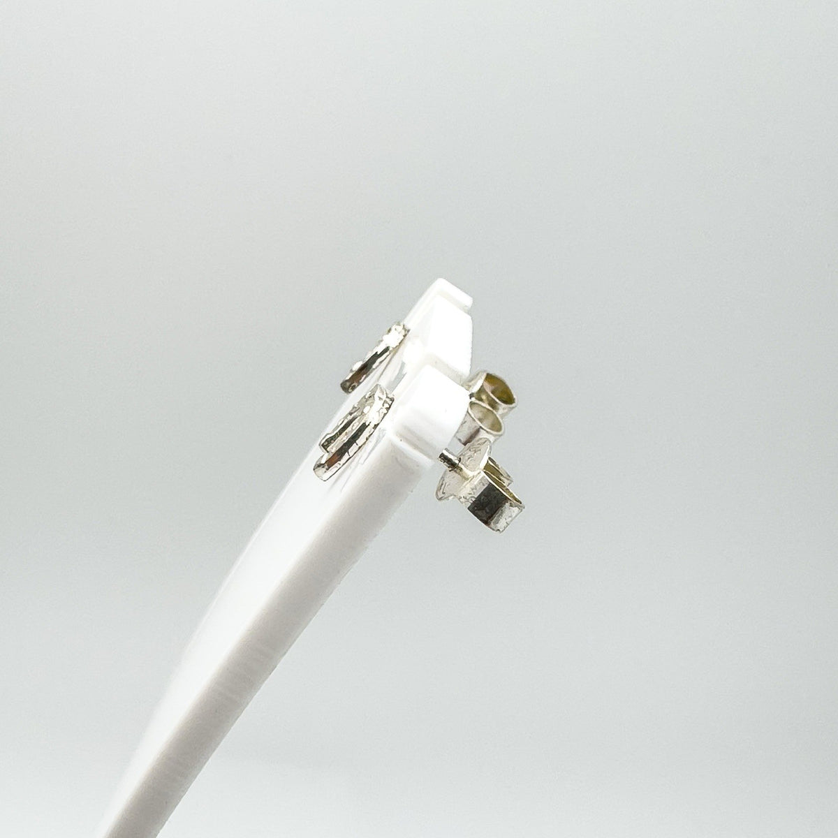 Side view of sterling silver mini horseshoe studs on display stand
