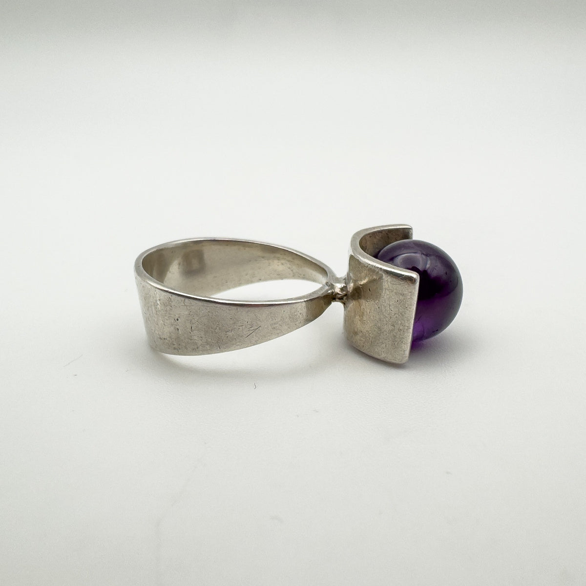 Side angle of silver modernist ring showing bold amethyst ball setting