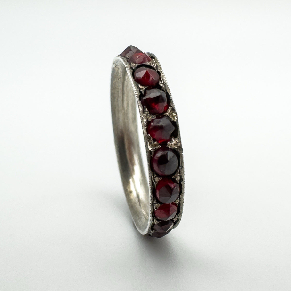 Detailed side view of full eternity garnet ring with antique hand-cut stones