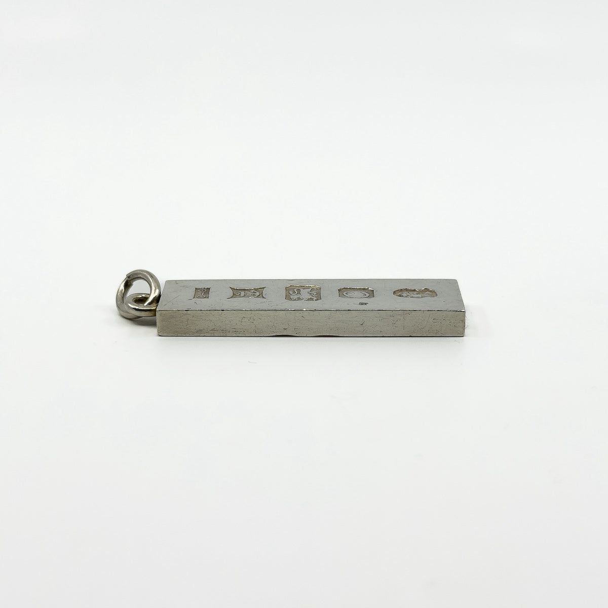 Hallmarked side of vintage sterling silver ingot pendant shown from a low angle