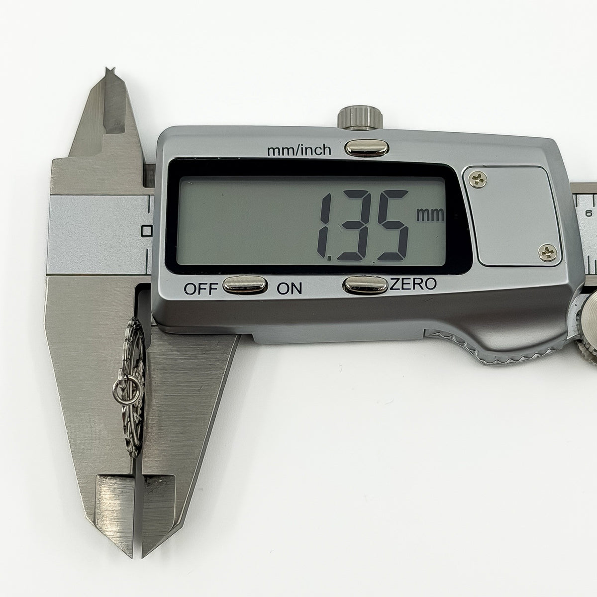 Digital caliper measuring the vintage sterling silver St Christopher pendant depth at approximately 1.35mm.