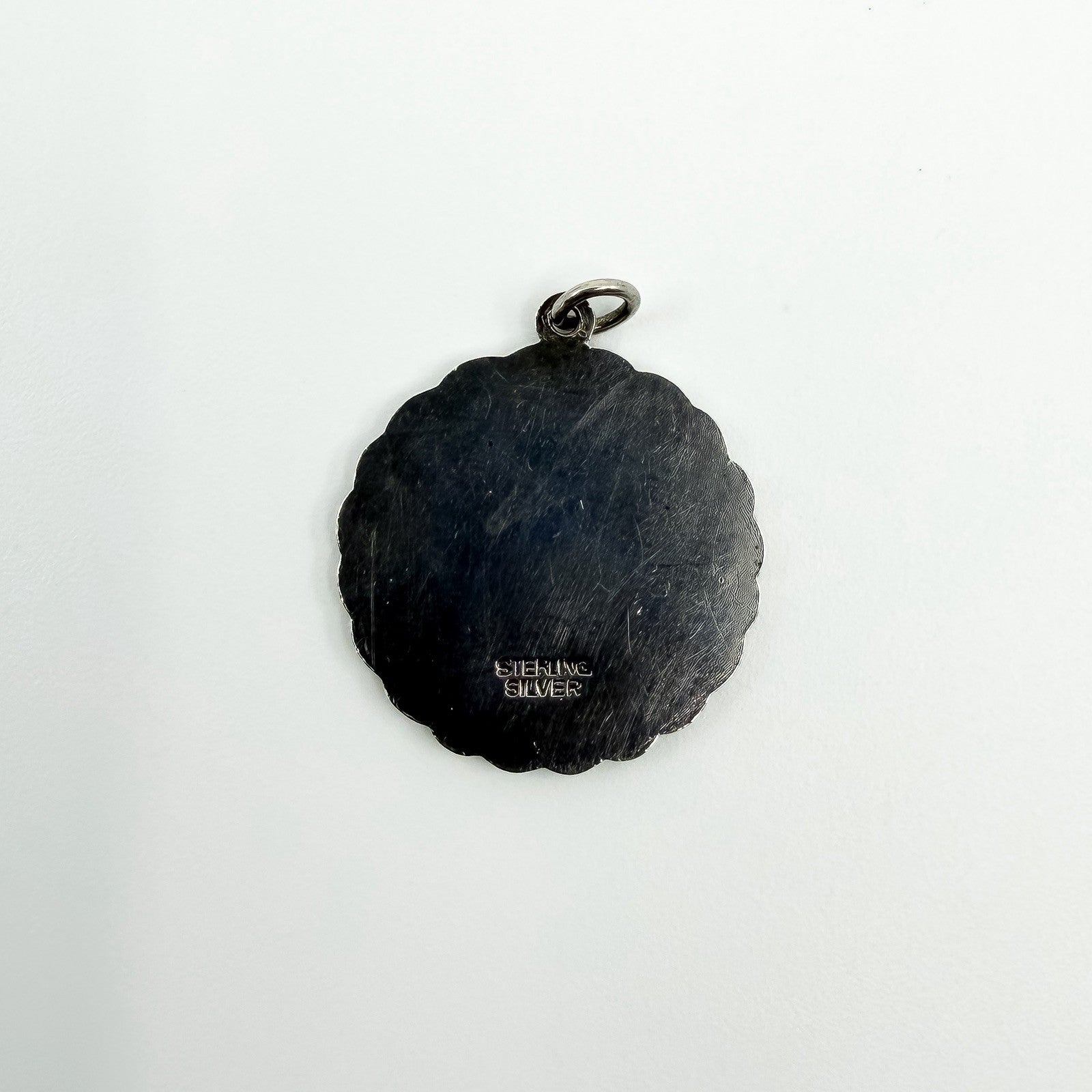 Close up of the back of vintage St Christopher pendant showing the Sterling Silver stamp.