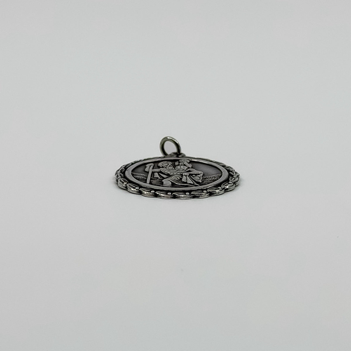 Low side view of vintage sterling silver St Christopher pendant charm with raised front detail.
