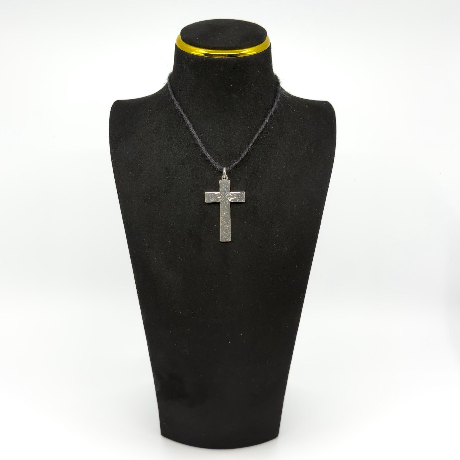 Vintage sterling silver engraved cross pendant shown on a black display bust.