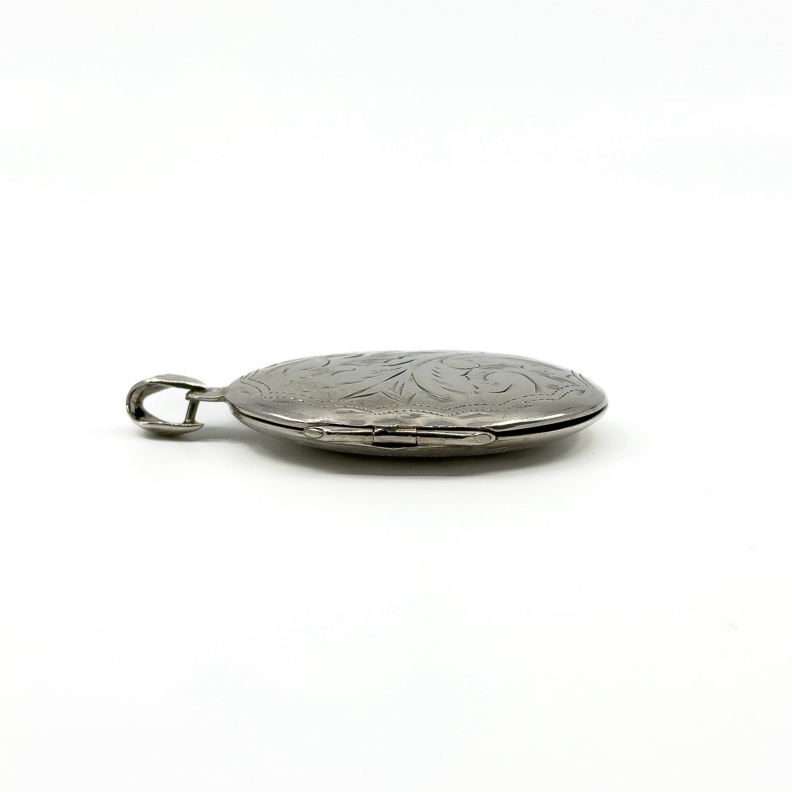 Side view of the sterling silver oval photo locket showing the hinge and engraved front
