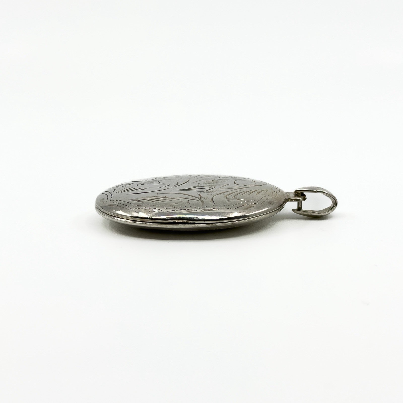 Side profile of a sterling silver oval photo locket showing its chunky depth and bail