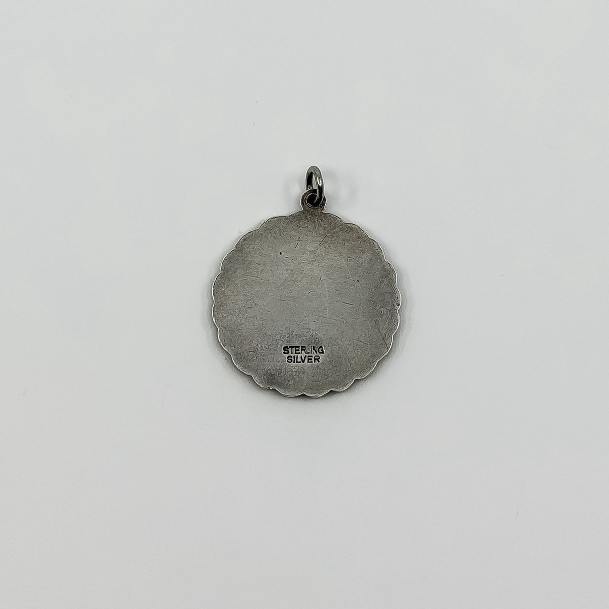 Back of vintage St Christopher pendant charm showing Sterling Silver stamp and scalloped edge.