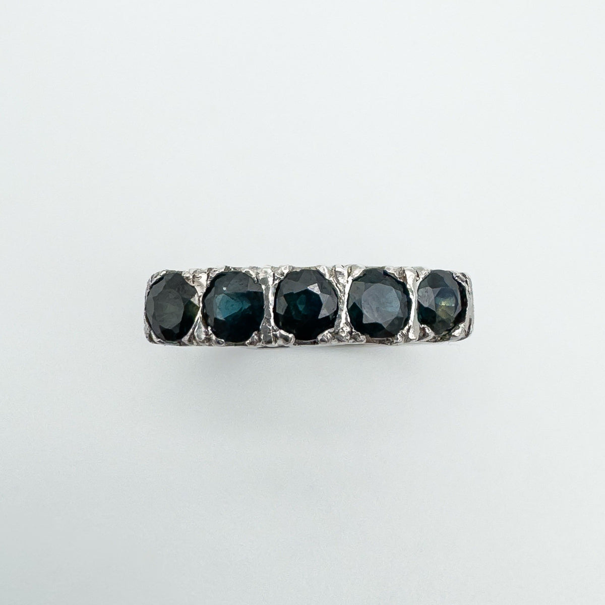 Overhead view of five flush-set sapphires in a vintage sterling silver band
