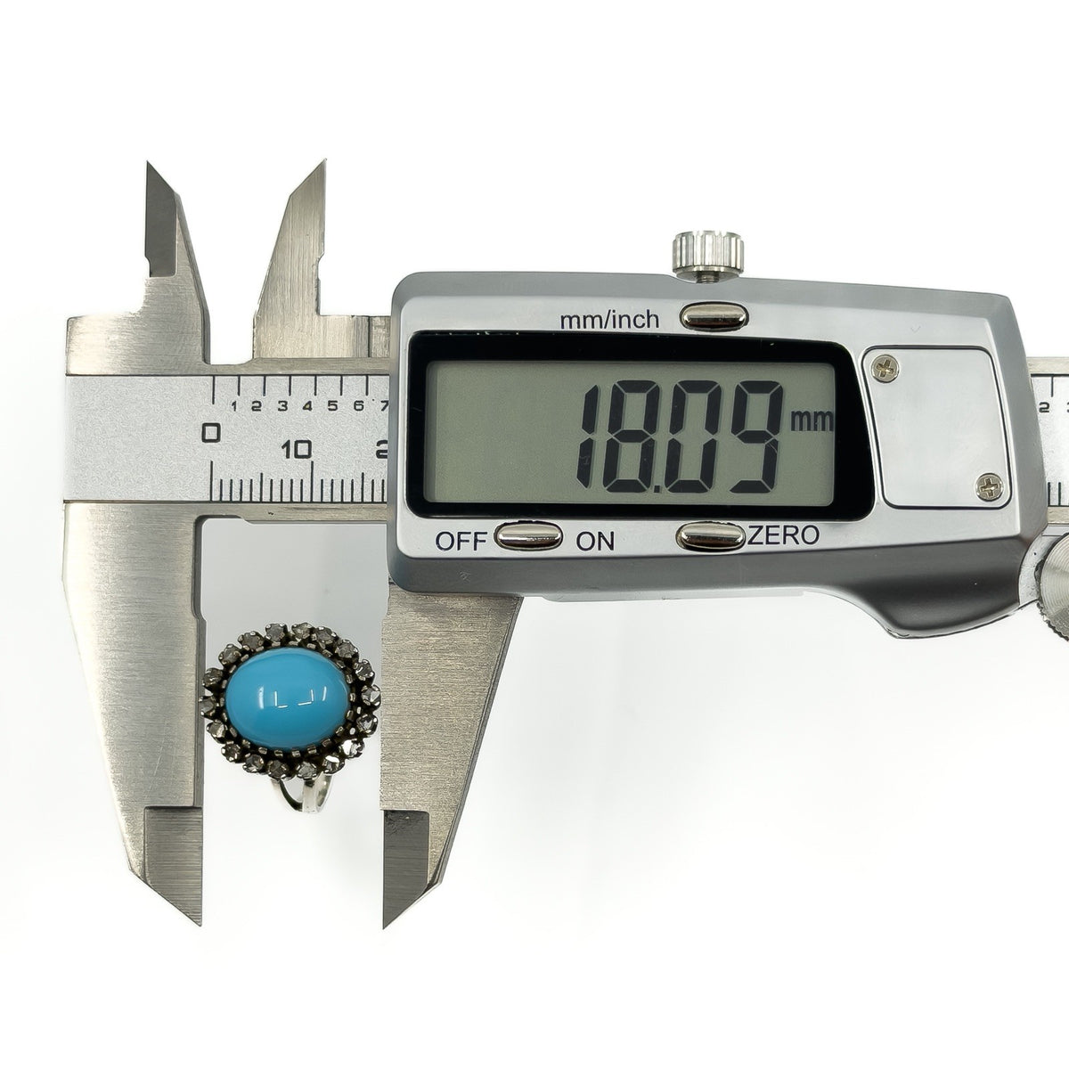 Calipers showing the turquoise diamond halo ring head measuring approximately 18mm