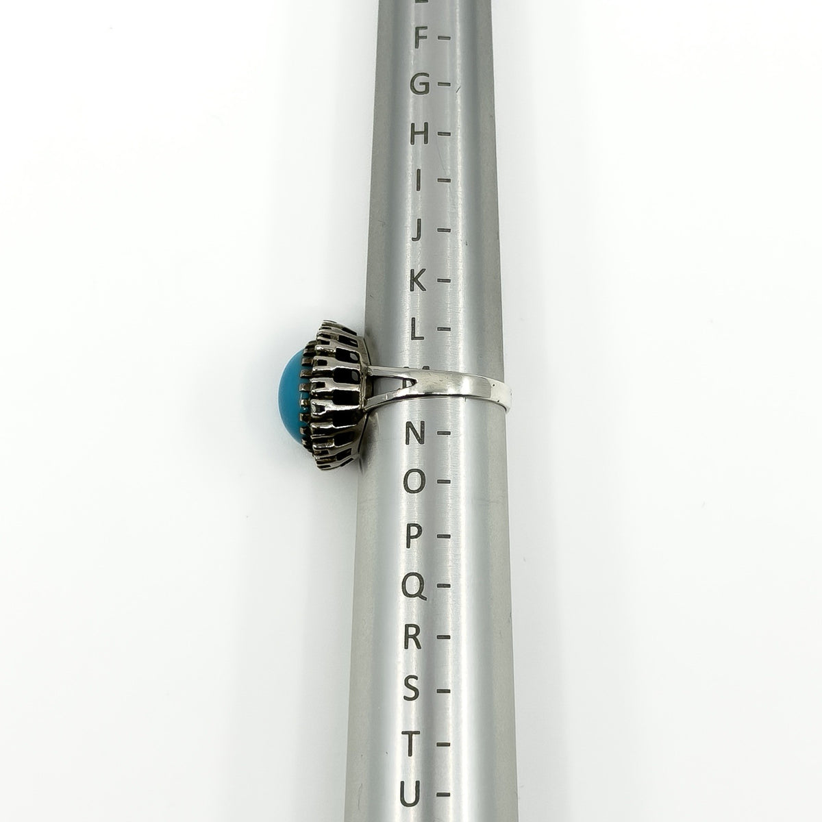 Side view of the sterling silver turquoise diamond halo ring on a UK ring mandrel