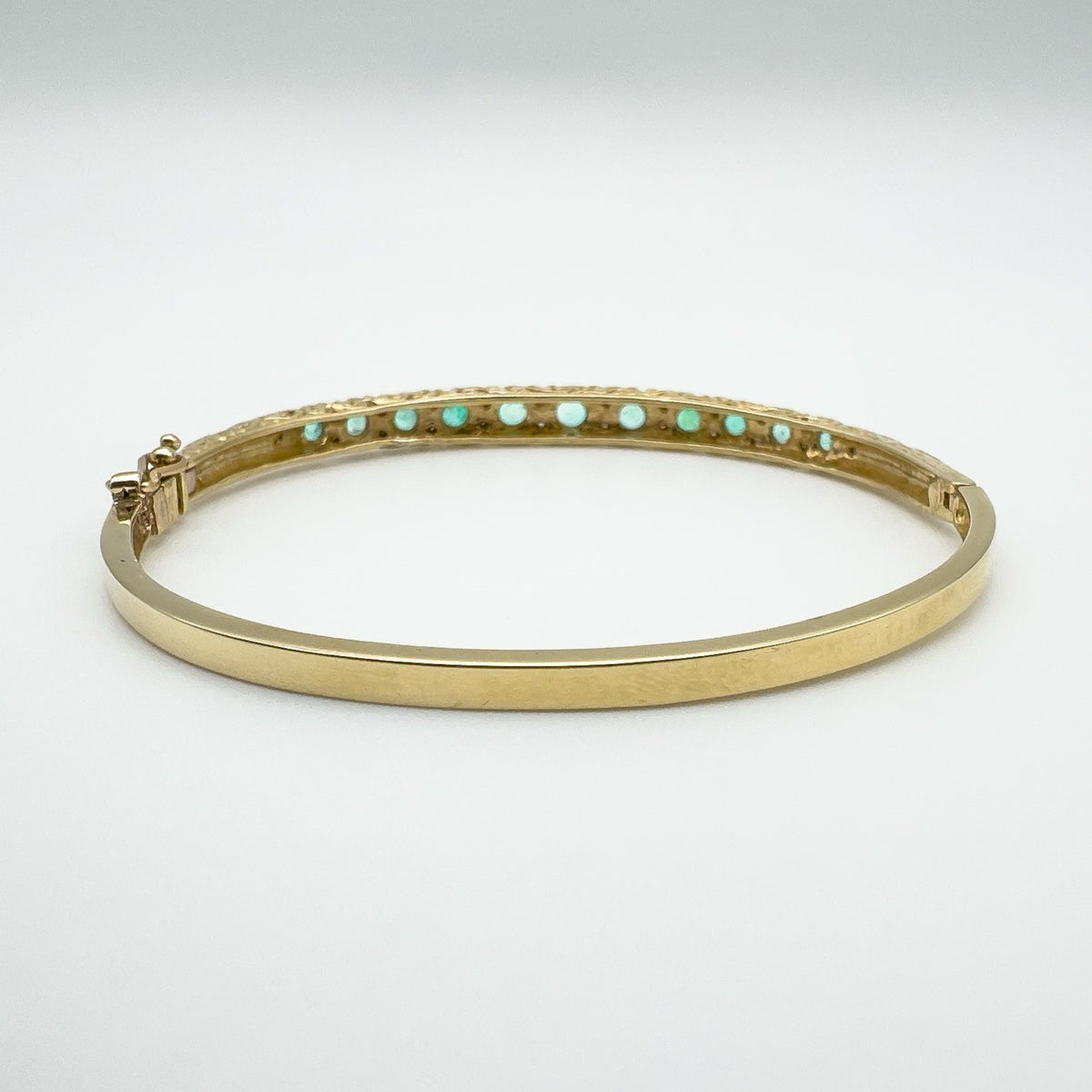 Back view of gemstone settings on vintage gold emerald bangle