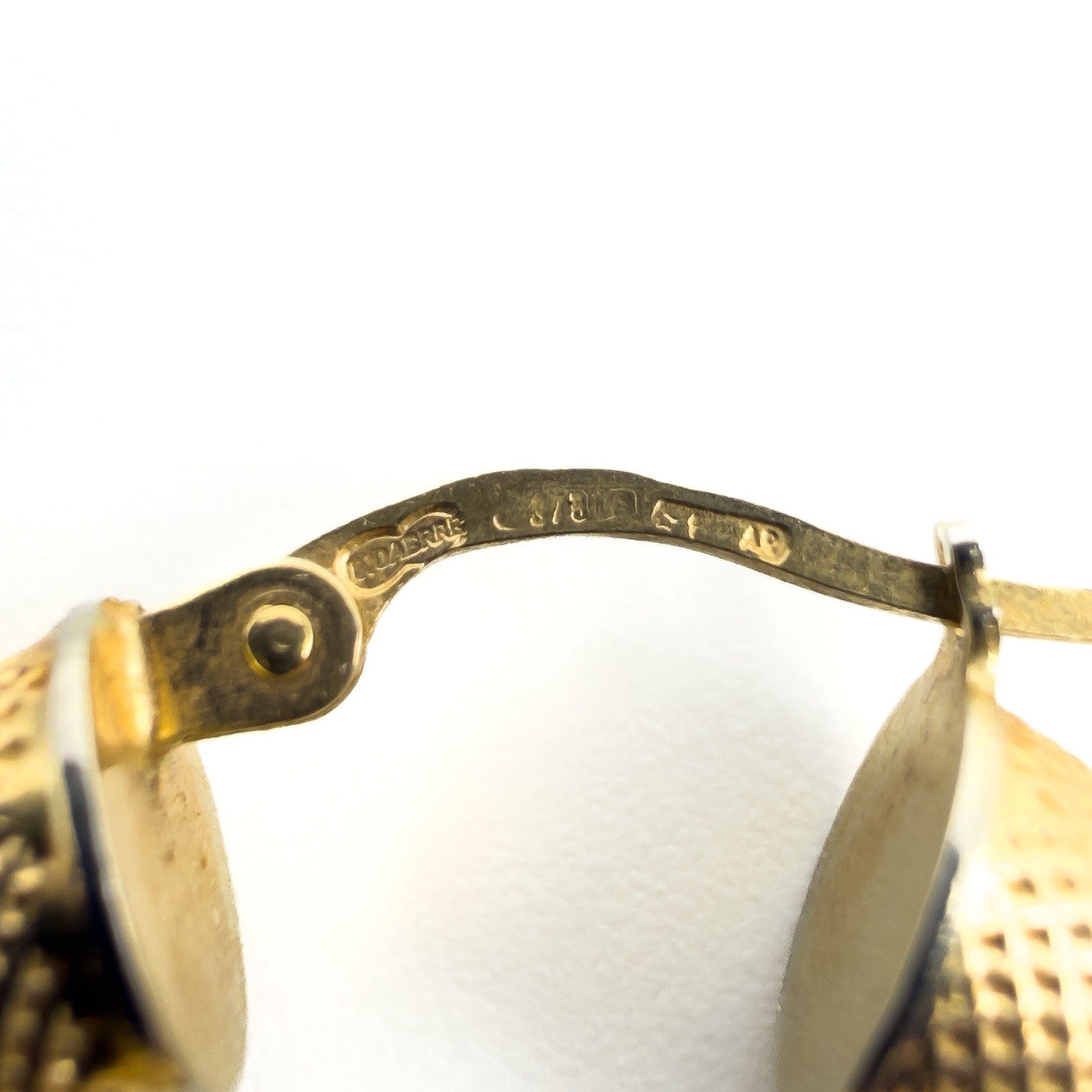 Close up of UnoAErre 375 hallmark on vintage 9ct gold mesh hoop earring
