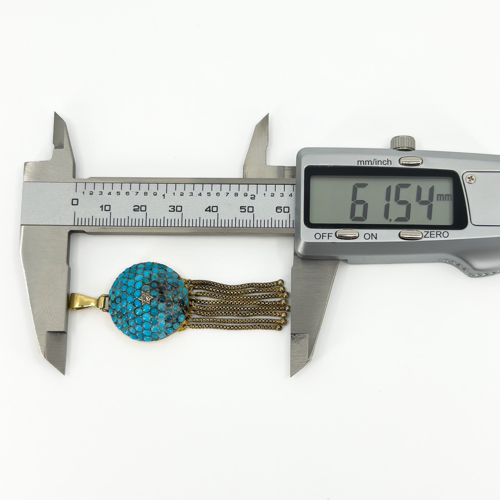 Digital caliper showing the Victorian turquoise and diamond tassel locket measuring approximately 61.54mm long.