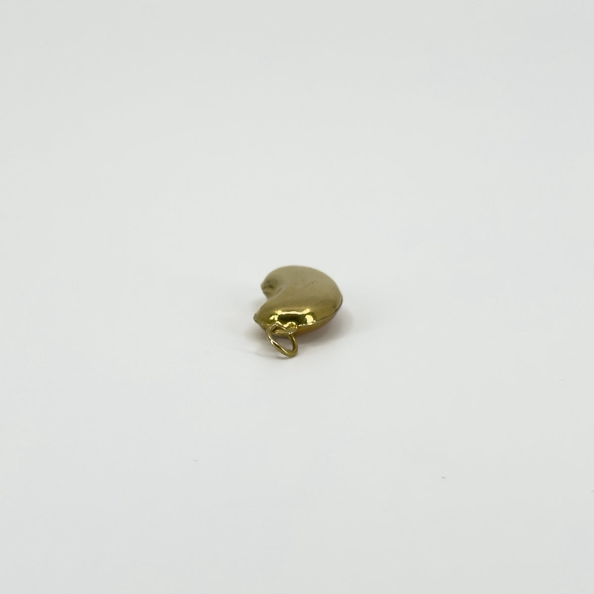 Angled view of vintage 9ct gold lucky bean charm pendant showing its curved hollow form and gold hoop.