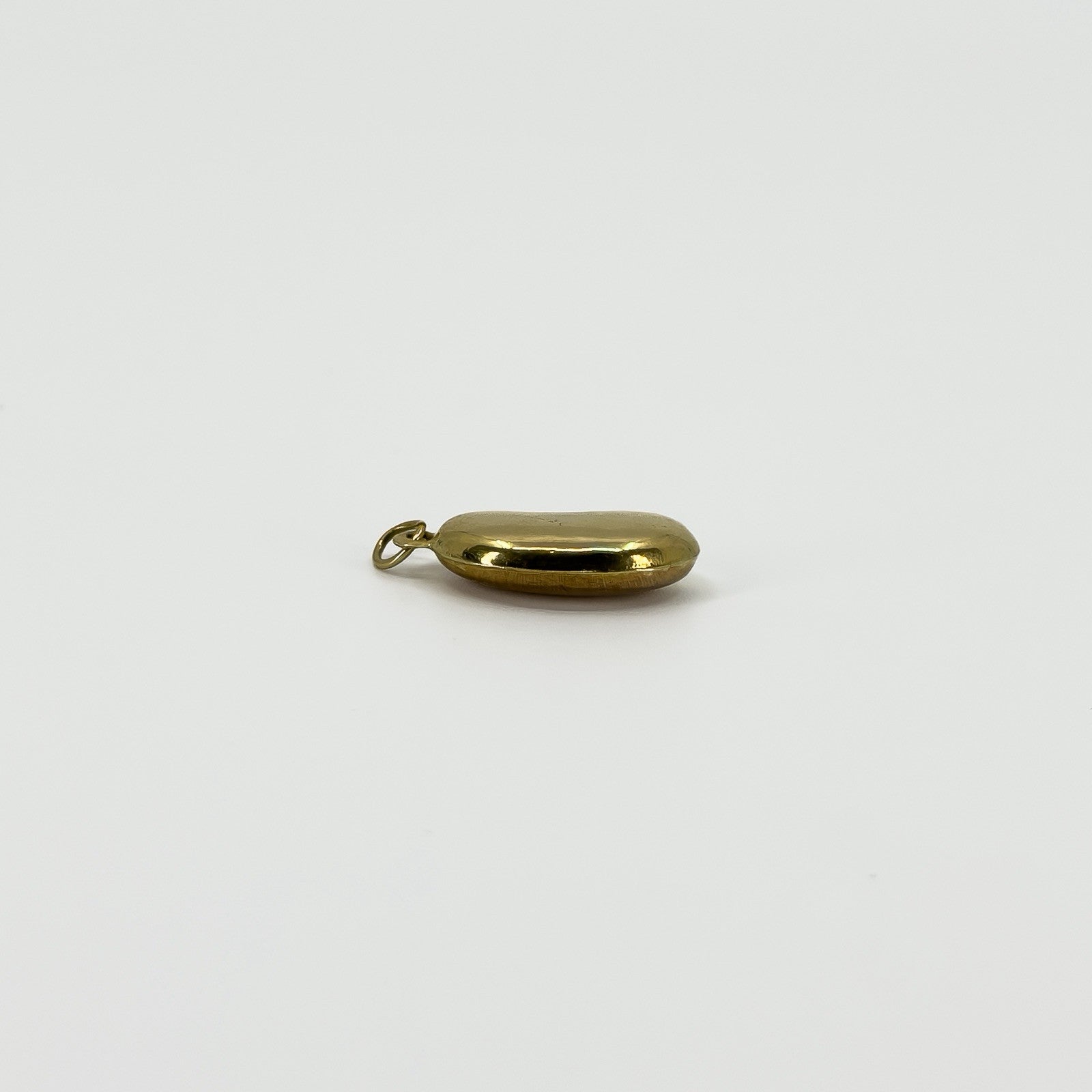 Edge view of vintage 9ct gold lucky bean charm pendant showing the rounded hollow construction and hoop fitting.