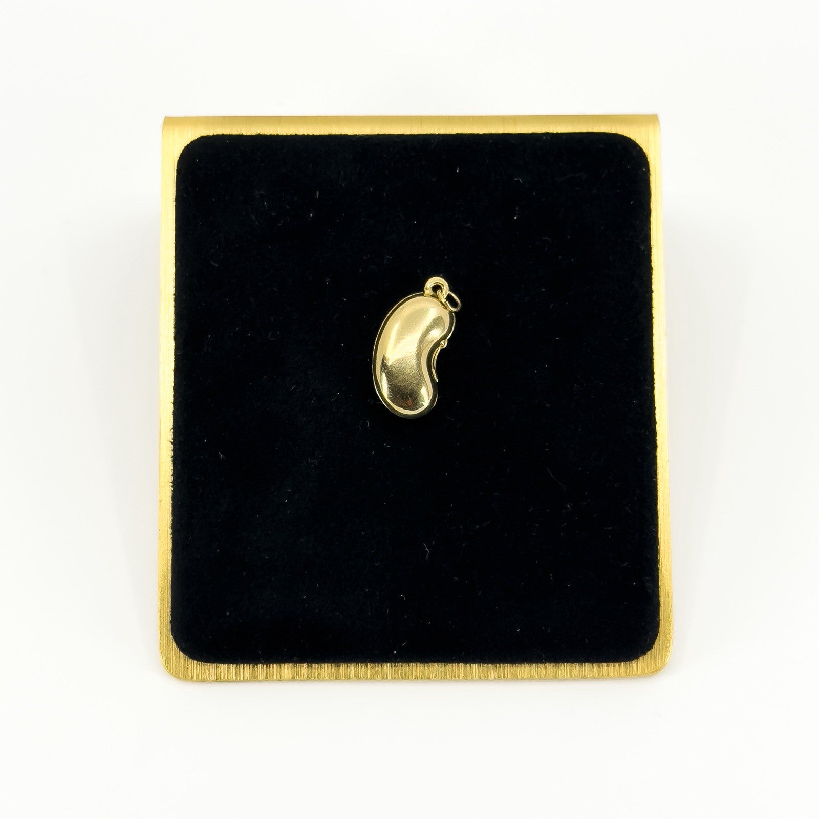 Vintage 9ct gold lucky bean charm pendant displayed on black velvet with polished kidney bean form.