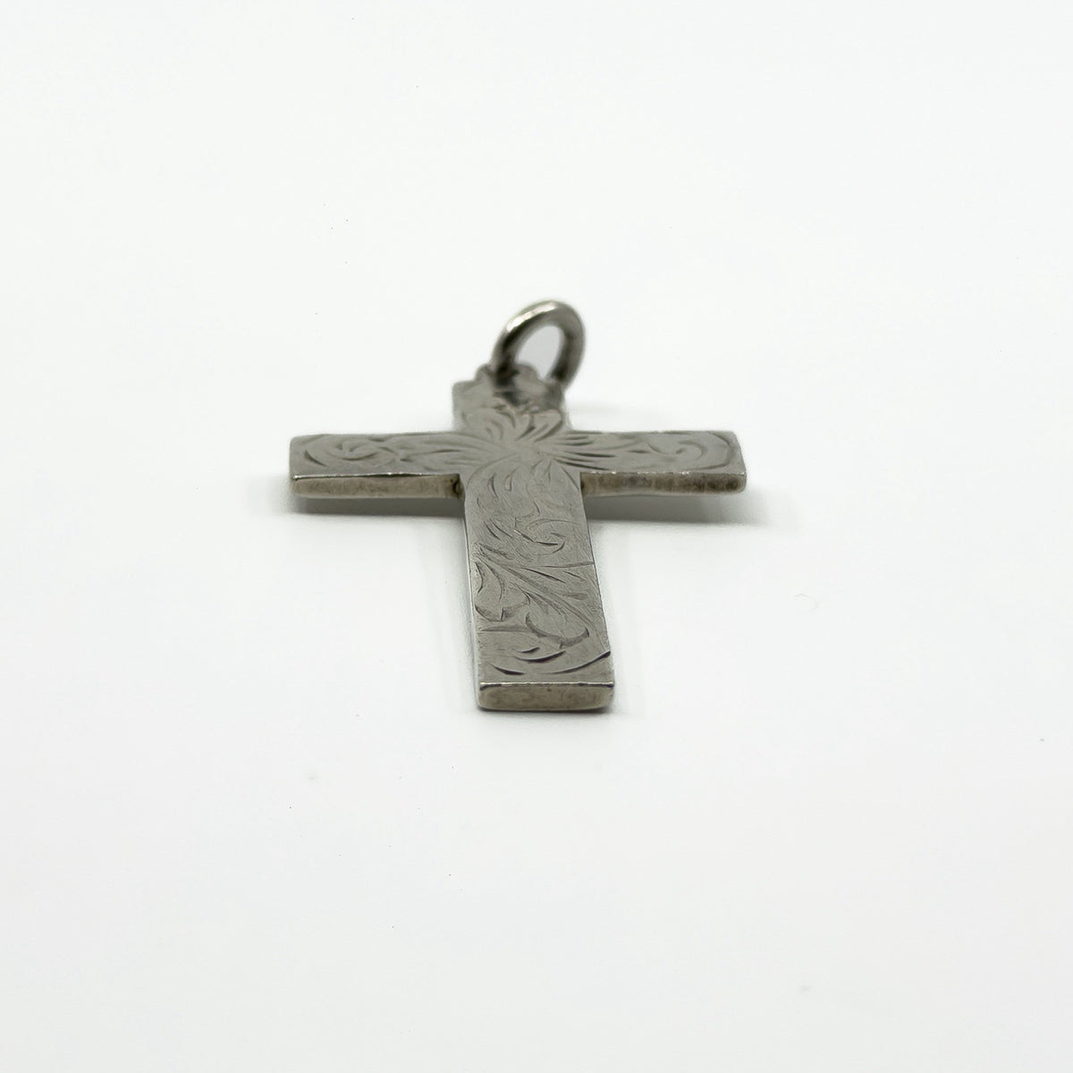 Close up of the engraved foliate detail on the vintage sterling silver cross pendant.