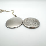 Side view of open sterling silver locket showing outer and inner detail