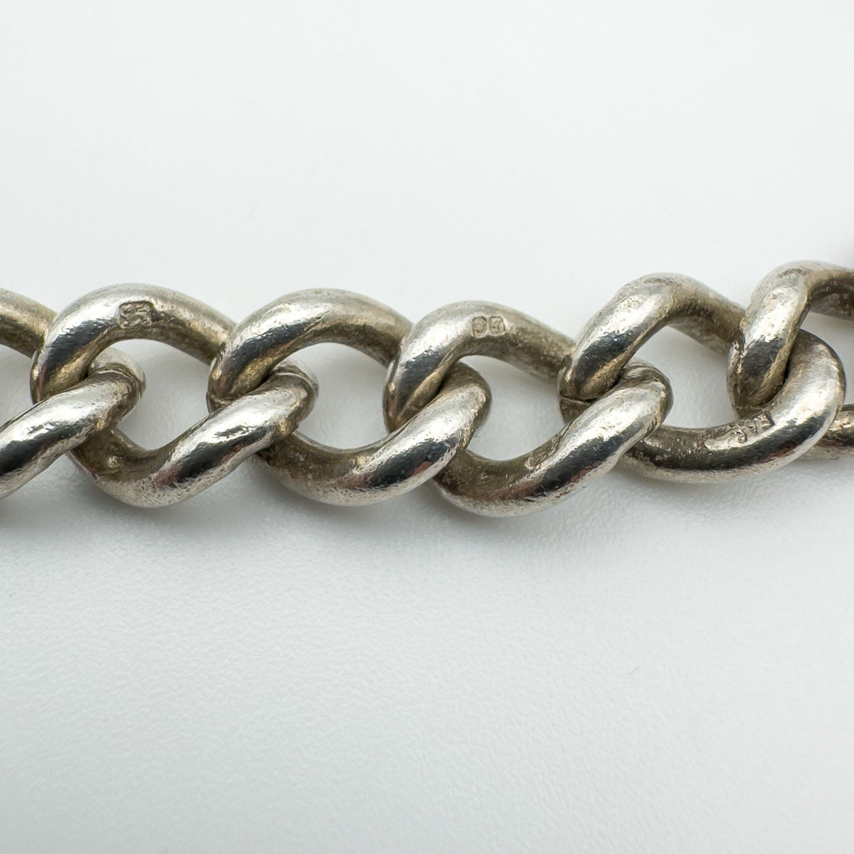 Close-up of vintage silver curb bracelet links with full British hallmarks