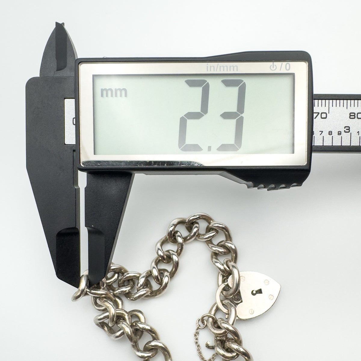 Caliper measuring link width of vintage silver bracelet at 2.3mm