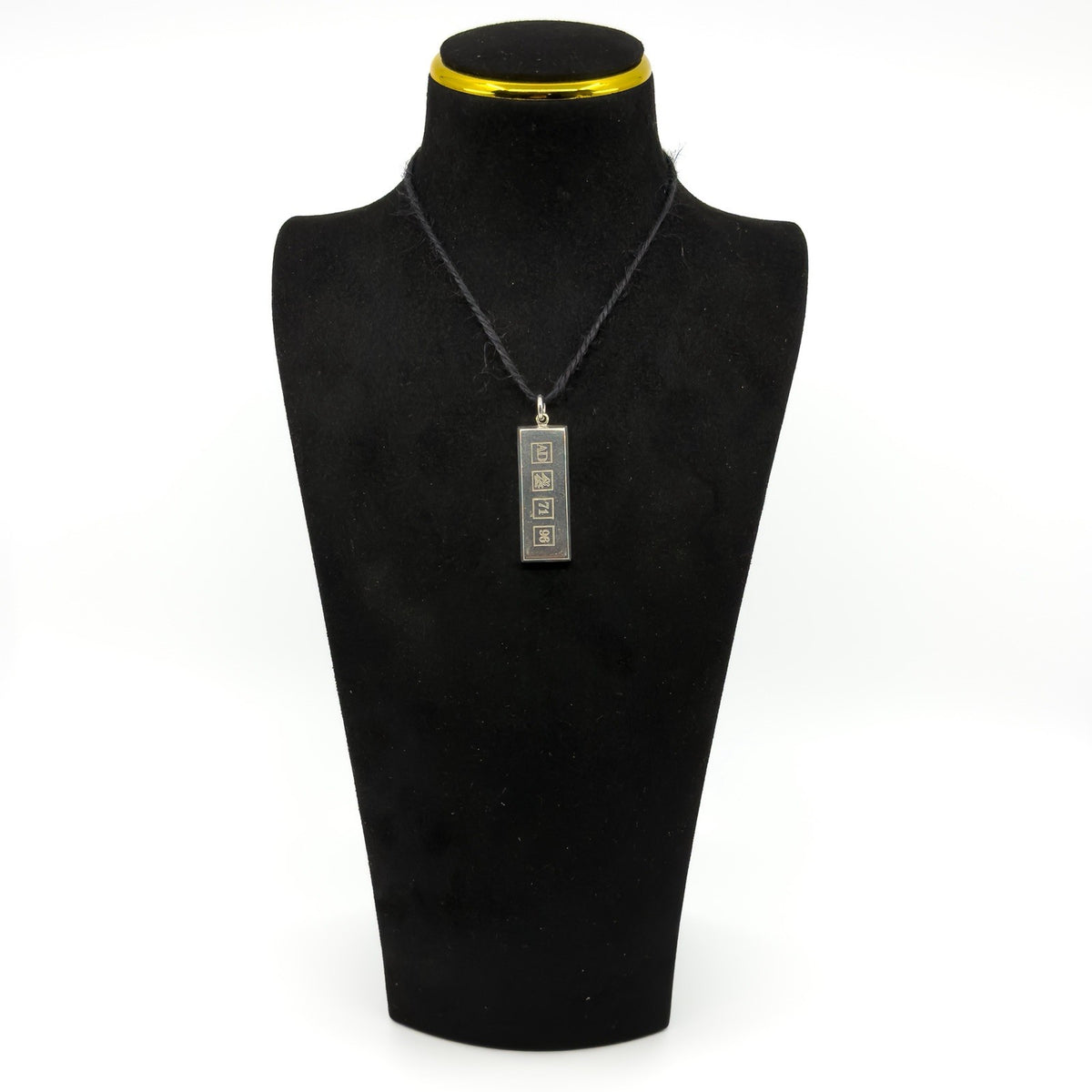 Vintage sterling silver ingot pendant on a black display bust, showing the front hallmark design.
