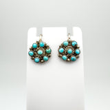 Vintage sterling silver earrings with circular turquoise design on display