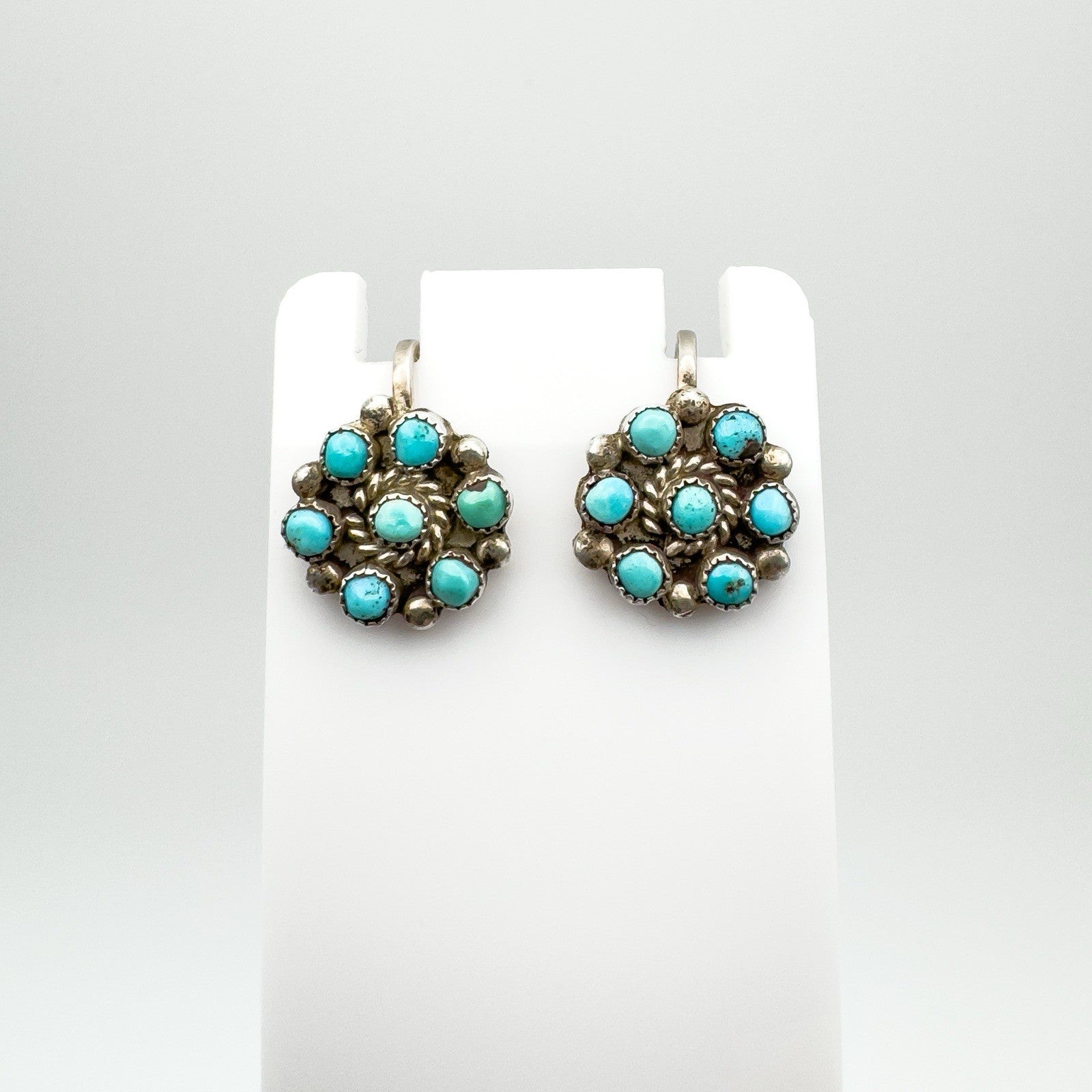 Vintage sterling silver earrings with circular turquoise design on display