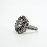 Angled front view of vintage platinum cluster ring with old cut centre and alternating round and baguette diamonds.