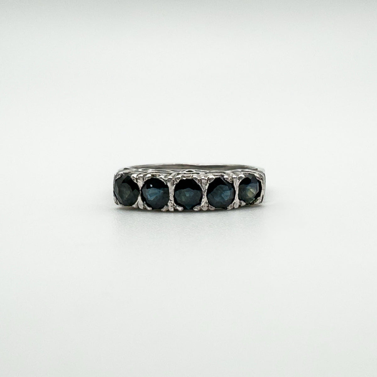 Close-up of vintage sterling silver ring with five dark blue sapphires in a claw setting