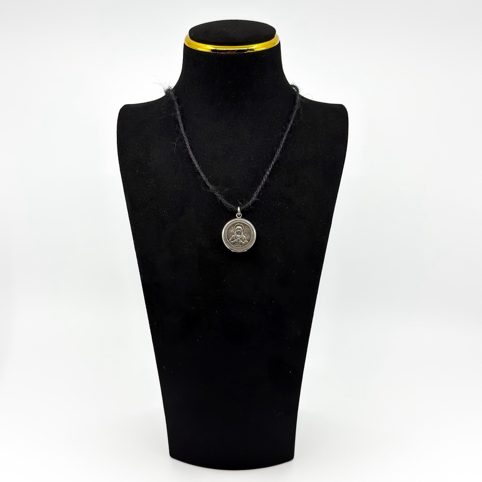 Vintage sterling silver Virgin Mary Christian photo locket pendant shown on a black display bust.