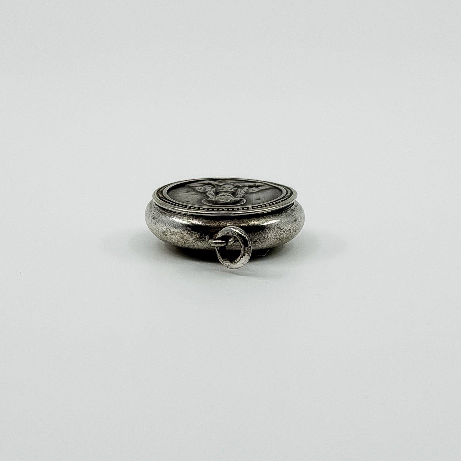 Low side view of vintage sterling silver Virgin Mary photo locket pendant with jump ring.