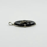 Side view of vintage 14ct white gold black onyx bow pendant showing the oval onyx profile.