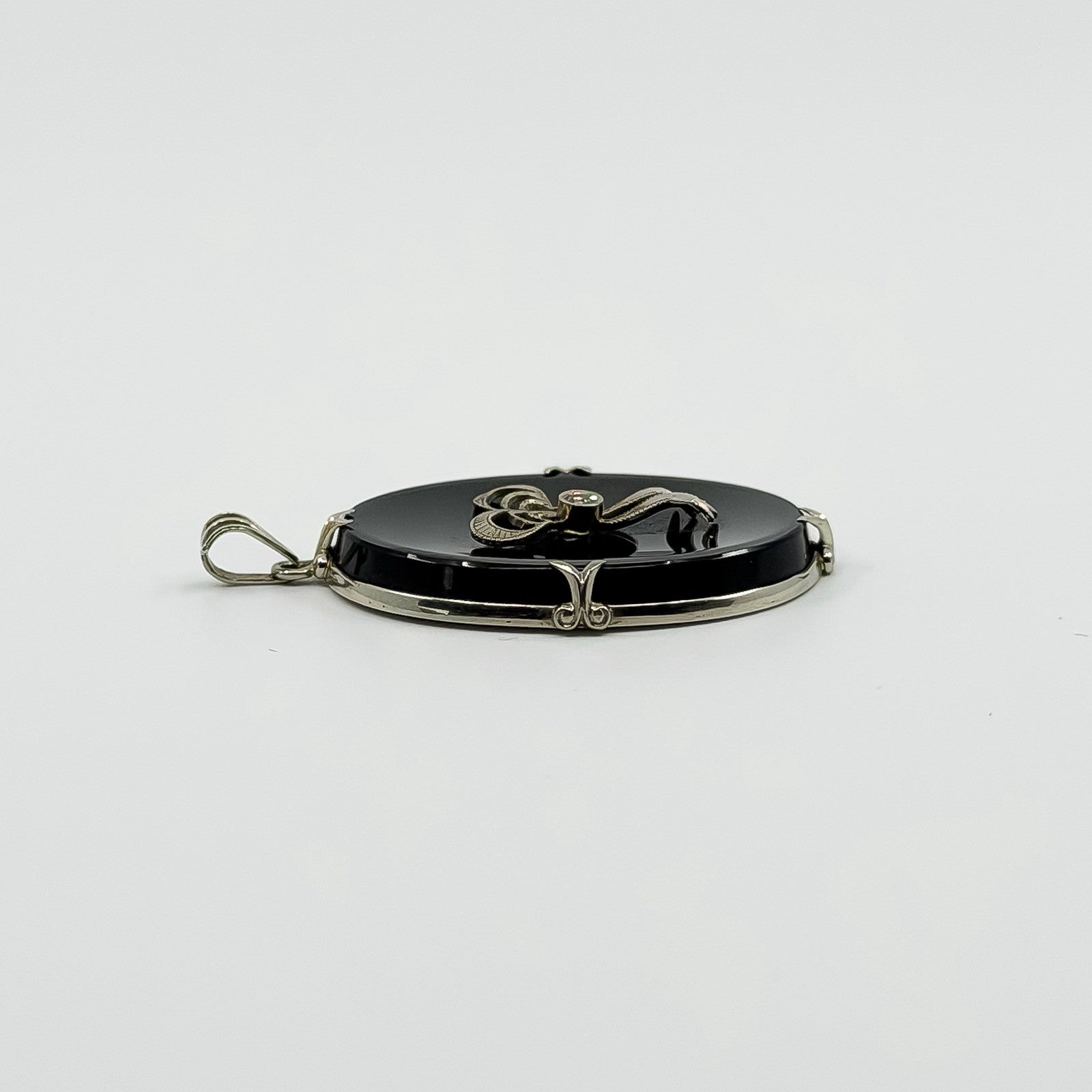 Side view of vintage 14ct white gold black onyx bow pendant showing the oval onyx profile.